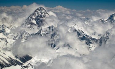 Hikers descending from K2 Base Camp with distant glacier views
