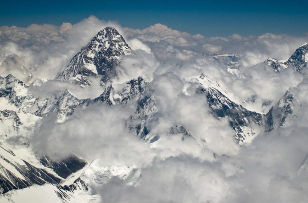 Hikers descending from K2 Base Camp with distant glacier views