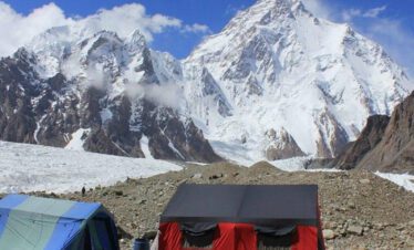 Hikers descending from K2 Base Camp with distant glacier views