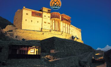 Crystal-clear waterfall surrounded by rocky cliffs and greenery in Skardu region
